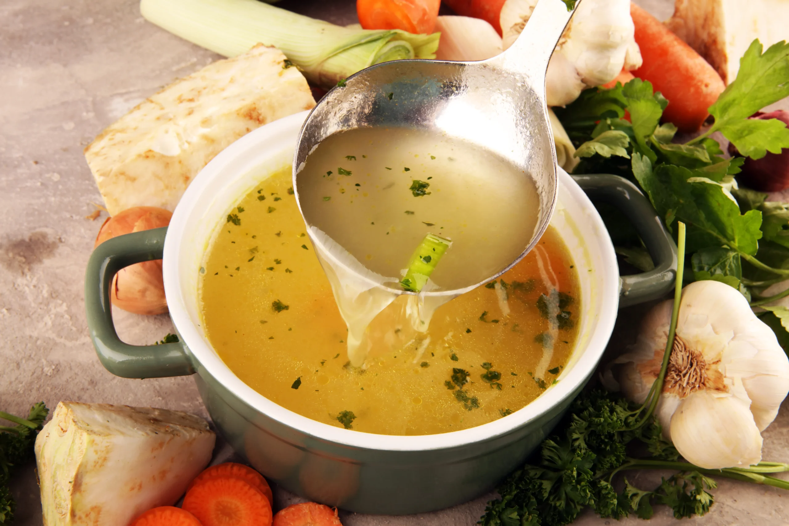 broth being scooped out of pot